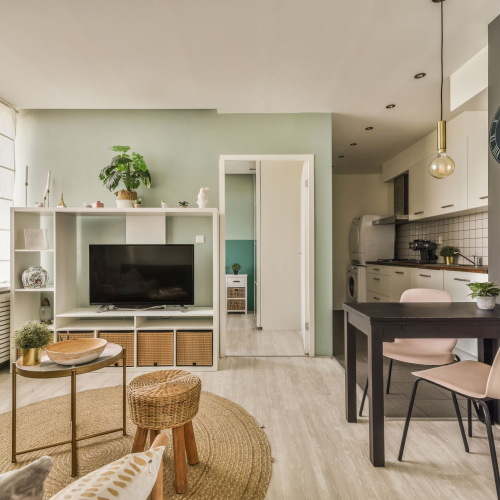 Table with chairs and flowers located near lounge area and kitchen in spacious room of contemporary apartment
